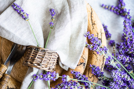 Summer time table set with vintage wooden plates and cutlery served on stone table and decorated with fresh lavender flowersの写真素材