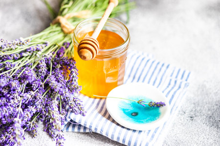 Summer lavandula honey in glass jar and flowers of Lavender plant on stone background with copy spaceの写真素材