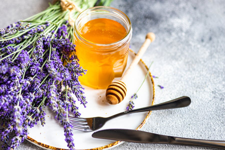 Summer lavandula honey in glass jar and flowers of Lavender plant on stone background with copy spaceの写真素材