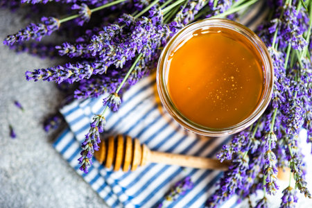 Summer lavandula honey in glass jar and flowers of Lavender plant on stone background with copy spaceの写真素材