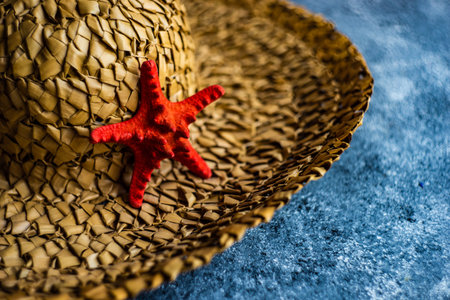 Summer travel concept with straw hat and red sea star on concrete background with copy spaceの写真素材