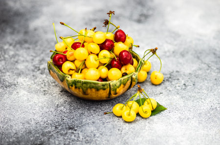 Ripe organic sweet cherries in a bowl on concrete background with copy spaceの写真素材