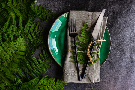 Summer rural table setting with plate and cutlery decorated with fresh fern leaves on stone background with copy spaceの写真素材