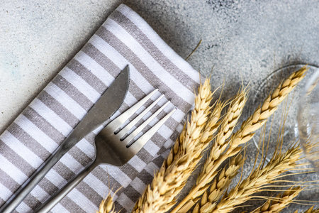 Rustic table setting with cutlery decorated with whear ears on concrete background with copy spaceの写真素材