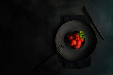 Served summer dessert with watermelon balls and mint in black stoneware on black backgroundの写真素材