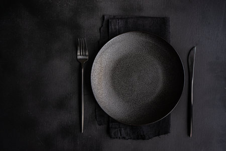 Table setting with plate, napkin and cutlery in black with copy spaceの写真素材