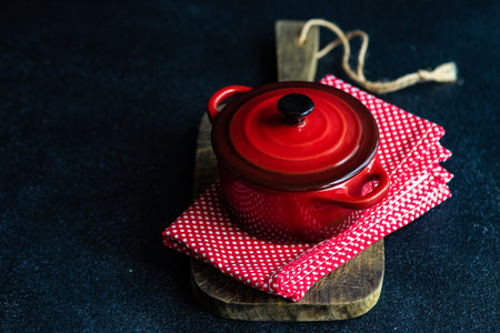 Red ceramic pot on dark concrete table as a cooking conceptの写真素材