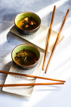 Asian style tea time drink concept with tea cups and chopsticks on white concrete background with copy spaceの写真素材