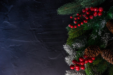 Christmas frame concept with xmas tree branches and red holiday decor on grey stone background with...