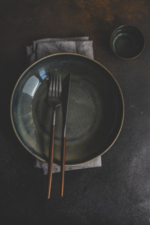 Rustic table setting with empty plate and cutlery set on concrete background with copy spaceの写真素材