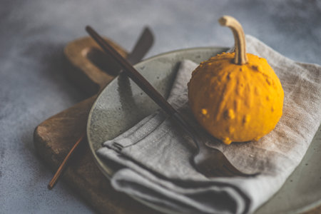 Autumnal table setting with bright pumpkin on rustic background with copy spaceの写真素材