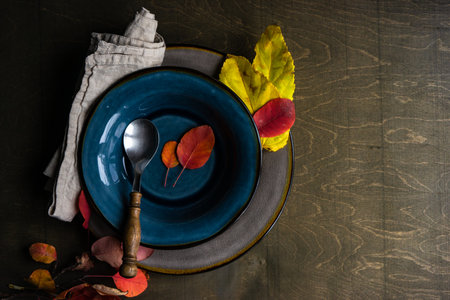 Autumnal place setting with yellow and red leaves on rustic background with copy spaceの写真素材