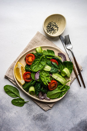 Healthy food salad with fresh organic spinach leaves with sesame seeds served in a bowl on concrete background with copy spaceの写真素材