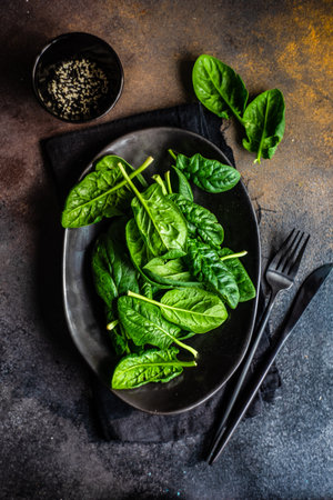 Black bowl with spinach fresh leaves and sesame seeds as a organic food conceptの写真素材