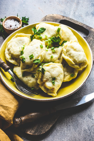 Traditional ukranian streamed potato vareniki or dumplings served in a bowl and green herbsの写真素材