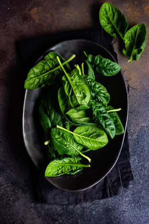 Black bowl with spinach fresh leaves and sesame seeds as a organic food conceptの写真素材