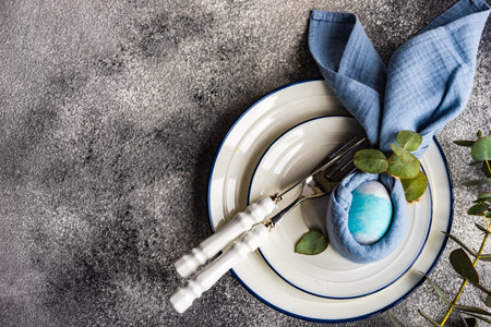 Easter festive dinner place setting on concrete table with copy space