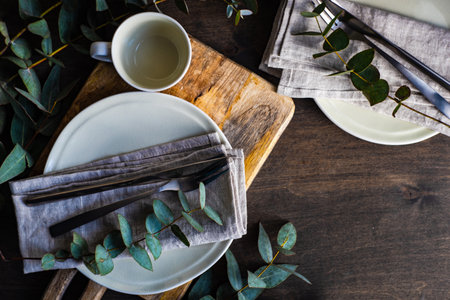 Place setting with fresh eucalyptus leaves on wooden tableの写真素材