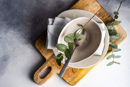 Minimalistic place setting with fresh eucalyptus leaves on concrete backroundの写真素材