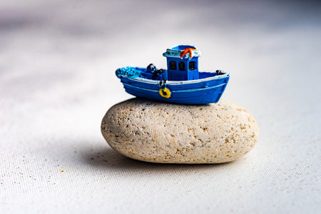 Summer card concept with blue sailor boat on sea stone on white background