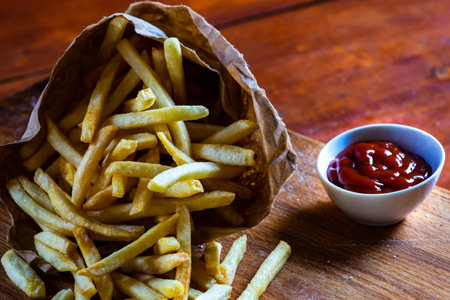 French fries and ketchup sauce on wooden table
