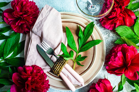 Summer background with place setting decorated with bright red peony flowersの写真素材
