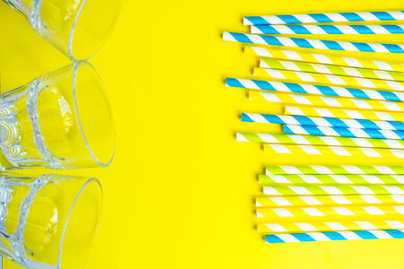 Yellow stripped recycling paper cocktail straws on the same color backgroundの写真素材