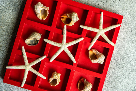 Red tic-tac-toe board game with seafish and shells as a summer background