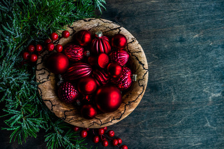 Christmas card concept with frame made with green fir branches, red decoration balls and berries on concrete backgroundの写真素材
