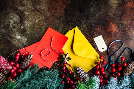 Christmas card concept with frame made with green fir branches, red decoration balls and berries on concrete backgroundの写真素材