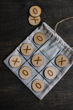 Tic-tac-toe board game and bag on wooden tableの写真素材