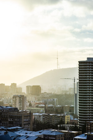 Dramatic sky over Tbilisi city's downtown in winter with sun rays and snowの写真素材