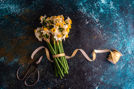 Bouquet of fresh spring daffodil flowers with ribbon on stone backgroundの写真素材