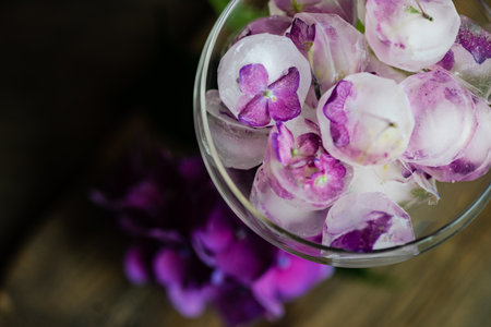 Glass with purple hydrangea flower ice cubes as a refreshing summer drink conceptの写真素材