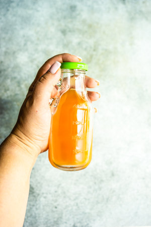 Woman hand holds homemade juice in the bottleの写真素材