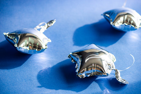 Silver star shaped baloons on blue background as a birthday party decorationの写真素材