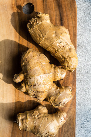 Raw ginger roots on wooden cutting board
