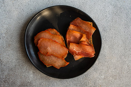 Toasts with rye bread and meat slices on the plate on concrete table