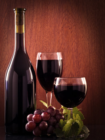 Red wine glass and bottle on a wooden background.の写真素材