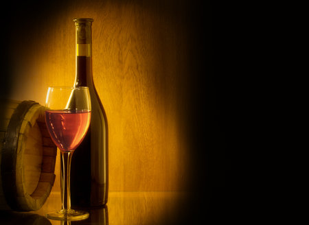 Red wine glass, barell and bottle on a wooden background. Low key still life.の写真素材