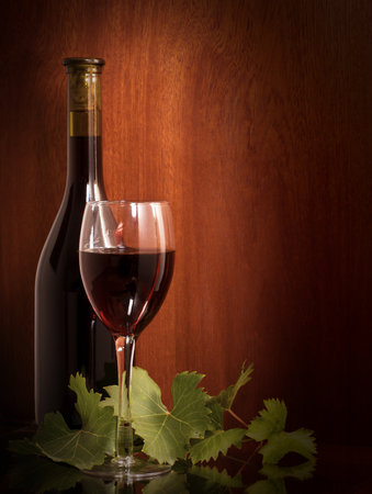 Red wine glass and bottle on a wooden background. Still life.の写真素材