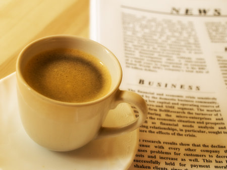 A cup of hot coffee, and newspaper. Wood table.の写真素材
