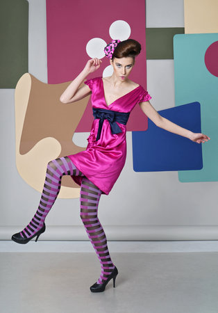 Eccentric outfit: short dress with open shoulders, headdress made of paper. She dances, bouncingÑ Multicolor background: circles, rectanglesの写真素材