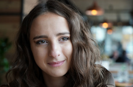 She smiles, thinking about something. Dark-brown eyes, natural makeup, healthy skin.の写真素材