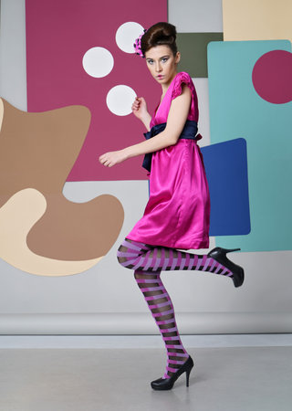 Color composition. Eccentric outfit. Short dress, high heels, striped tights. Simple shapes - circles, rectangles.の写真素材