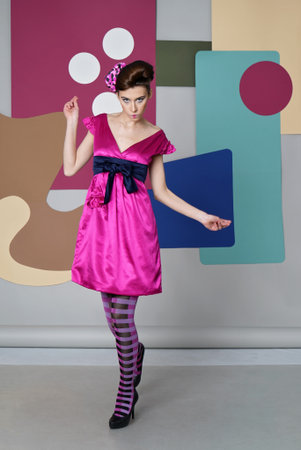 She dressed in short pink dress, striped tights, heels, hand and leg Ð¸ÑÑÐµÑ Backdrop: circles, rectangles, Egg chair.の写真素材