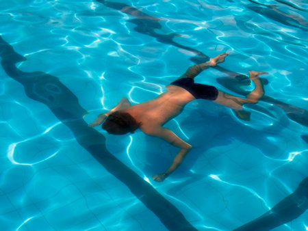 Refraction of light in water. Sun reflections in a pool water on a blue tile.の写真素材