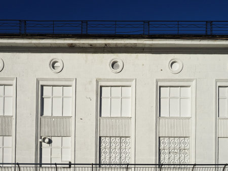White facade of the house with a wrought iron grating on a series of imaginary windows. Simple geometric figures: circles, lines, squares against the blue sky. Concept: white on the whiteの写真素材