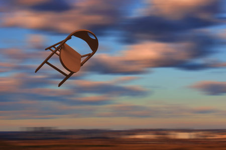 Chair flying in the sky. Brown - orange chair motion on blurred background. Yellow pink clowds. Concept: speed-up, velocityの写真素材