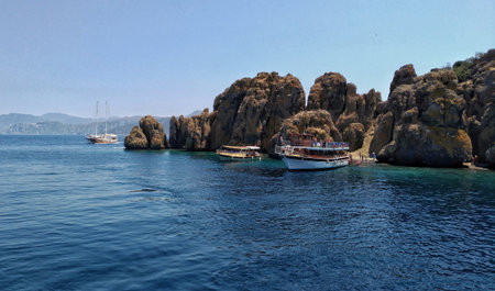Blue sky, pleasure yacht near sheer cliffs of island. This territory in Aegean Sea popular among tourists, thanks to unusual appearance and accessible caves on itの写真素材
